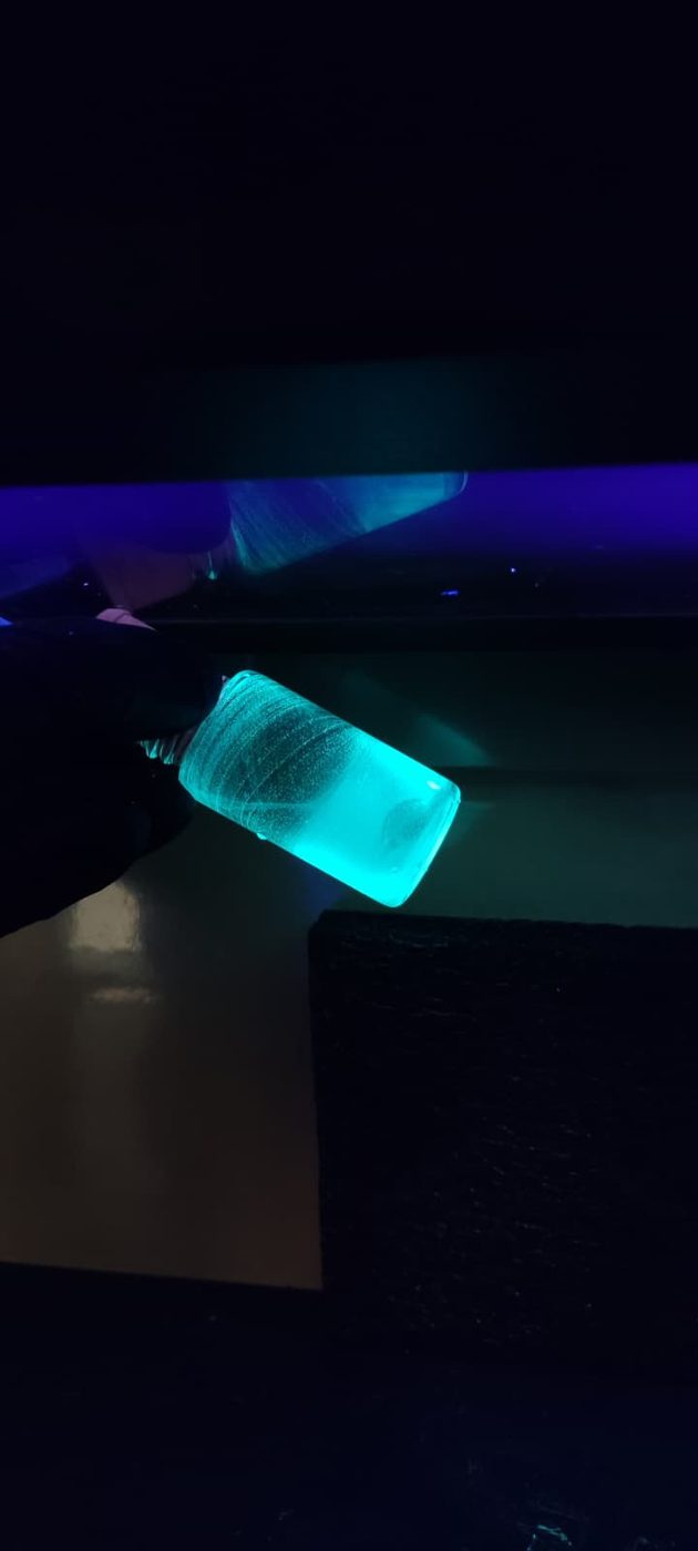 Vial glowing cyan under UV light